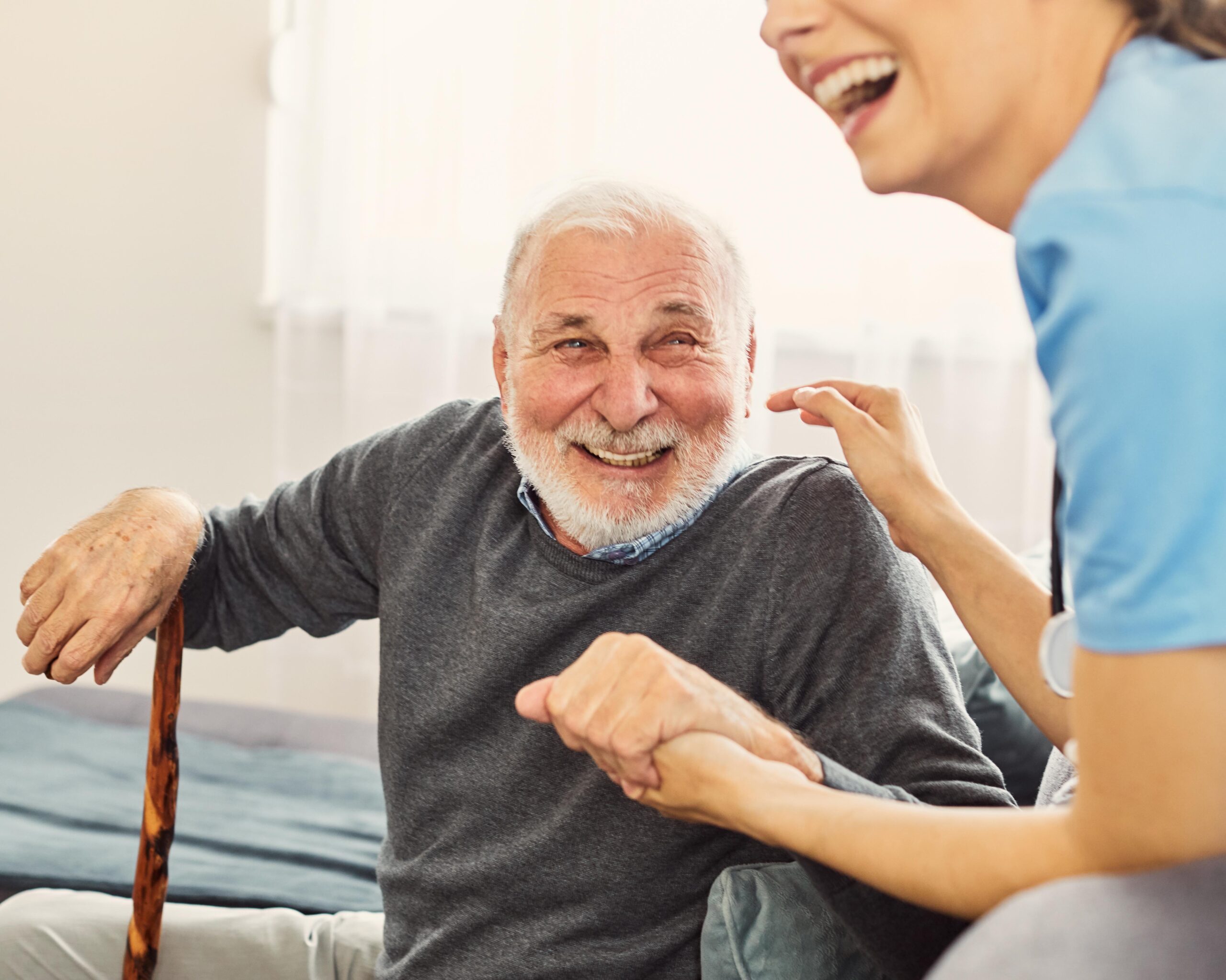 Doctor or nurse caregiver with senior man holding walking cane at home or nursing home