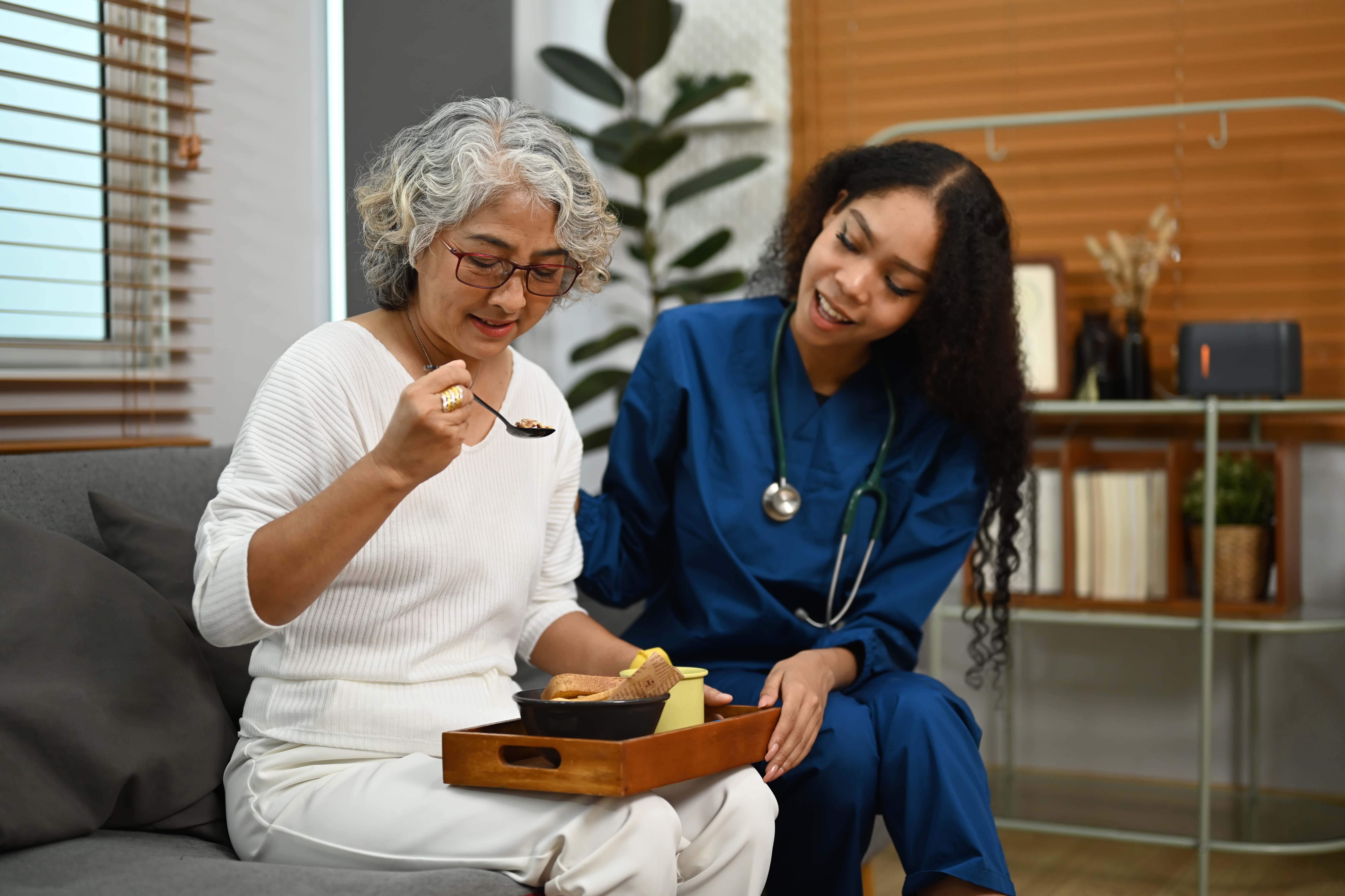 Attentive professional female caregiver taking care of elderly woman. Elderly healthcare concept.
